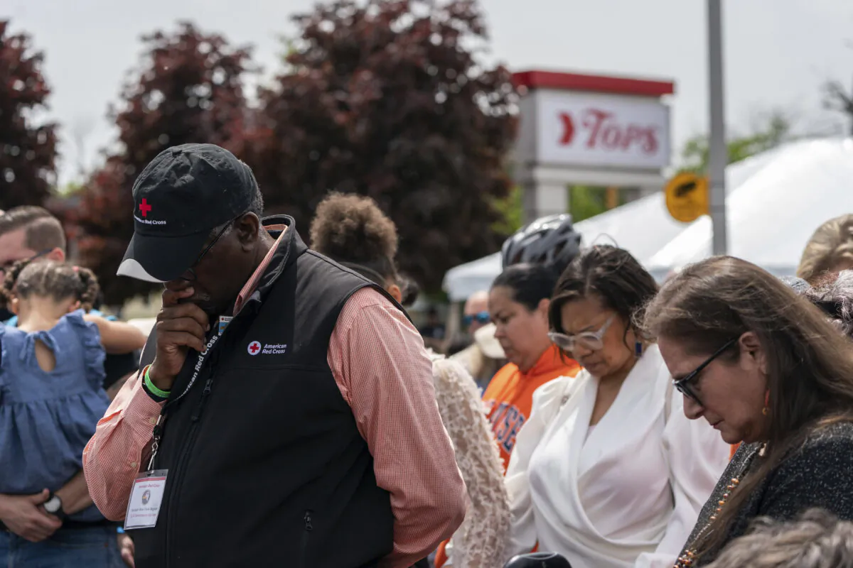 A crowd bows their heads for a moment of silence outside the Tops Friendly Market in Buffalo, N.Y., during a remembrance event on May 14, 2023. (Joshua Bessex/The Buffalo News via AP)