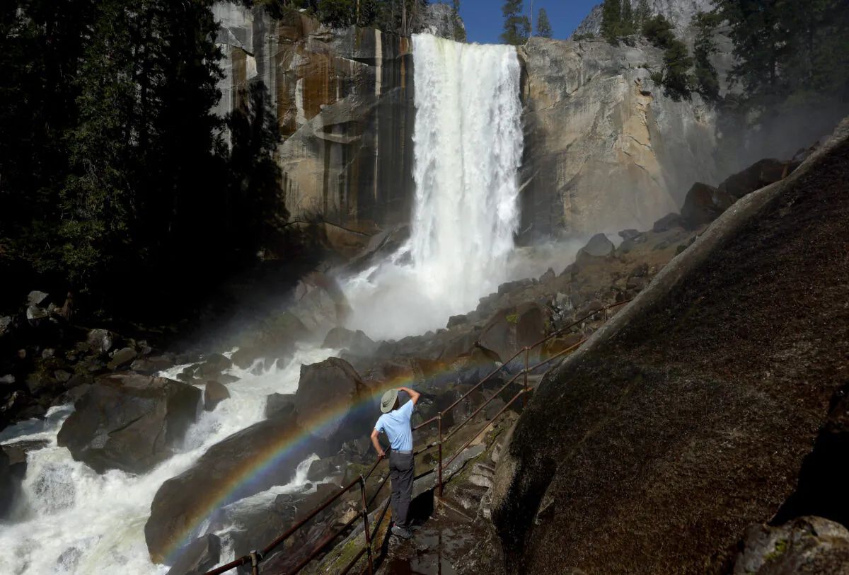 A person stands on a stairway leading to the top of Vernal Fall, with a rainbow visible, as warming temperatures have increased snowpack runoff in Yosemite National Park, Calif., on April 28, 2023. (Mario Tama/Getty Images)