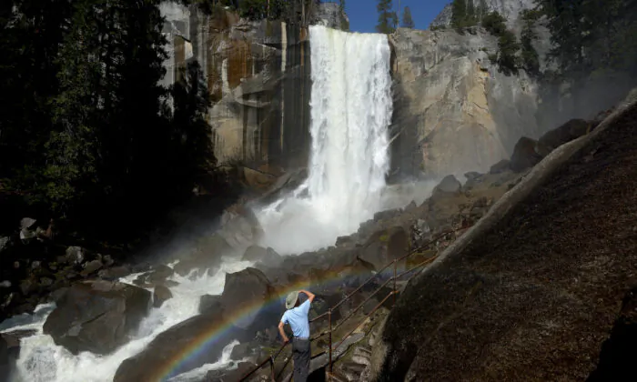 A person stands on a stairway leading to the top of Vernal Fall, with a rainbow visible, as warming temperatures have increased snowpack runoff in Yosemite National Park, Calif., on April 28, 2023. (Mario Tama/Getty Images)