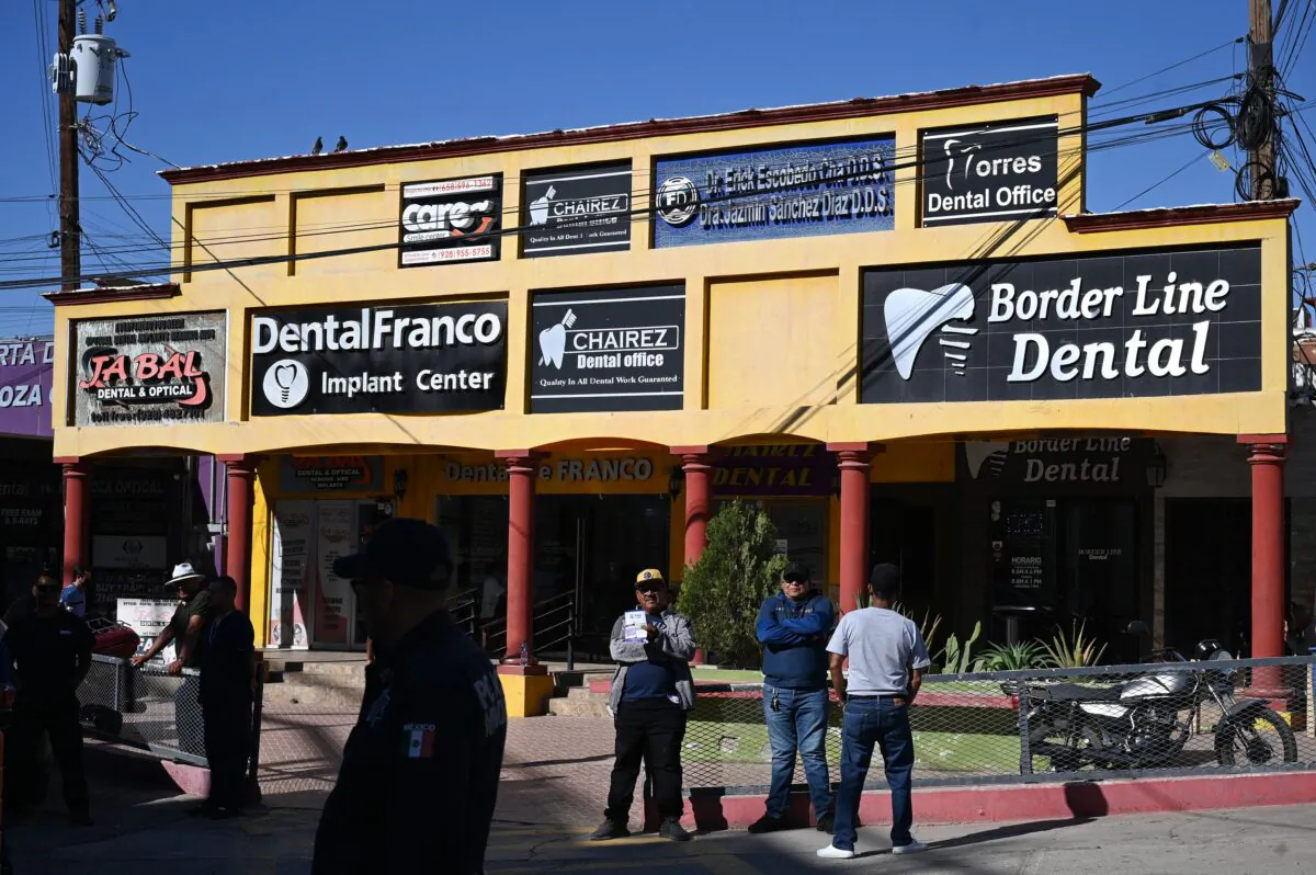 A tout holds a sign advertising dental services as he waits for American medical tourists to arrive from the border crossing checkpoint, in Los Algodones, Mexico, on April 11, 2023. (Robyn Beck/AFP via Getty Images)