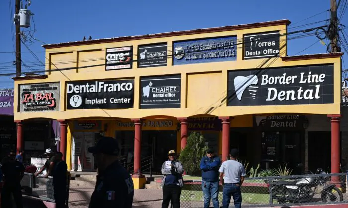 A tout holds a sign advertising dental services as he waits for American medical tourists to arrive from the border crossing checkpoint, in Los Algodones, Mexico, on April 11, 2023. (Robyn Beck/AFP via Getty Images)