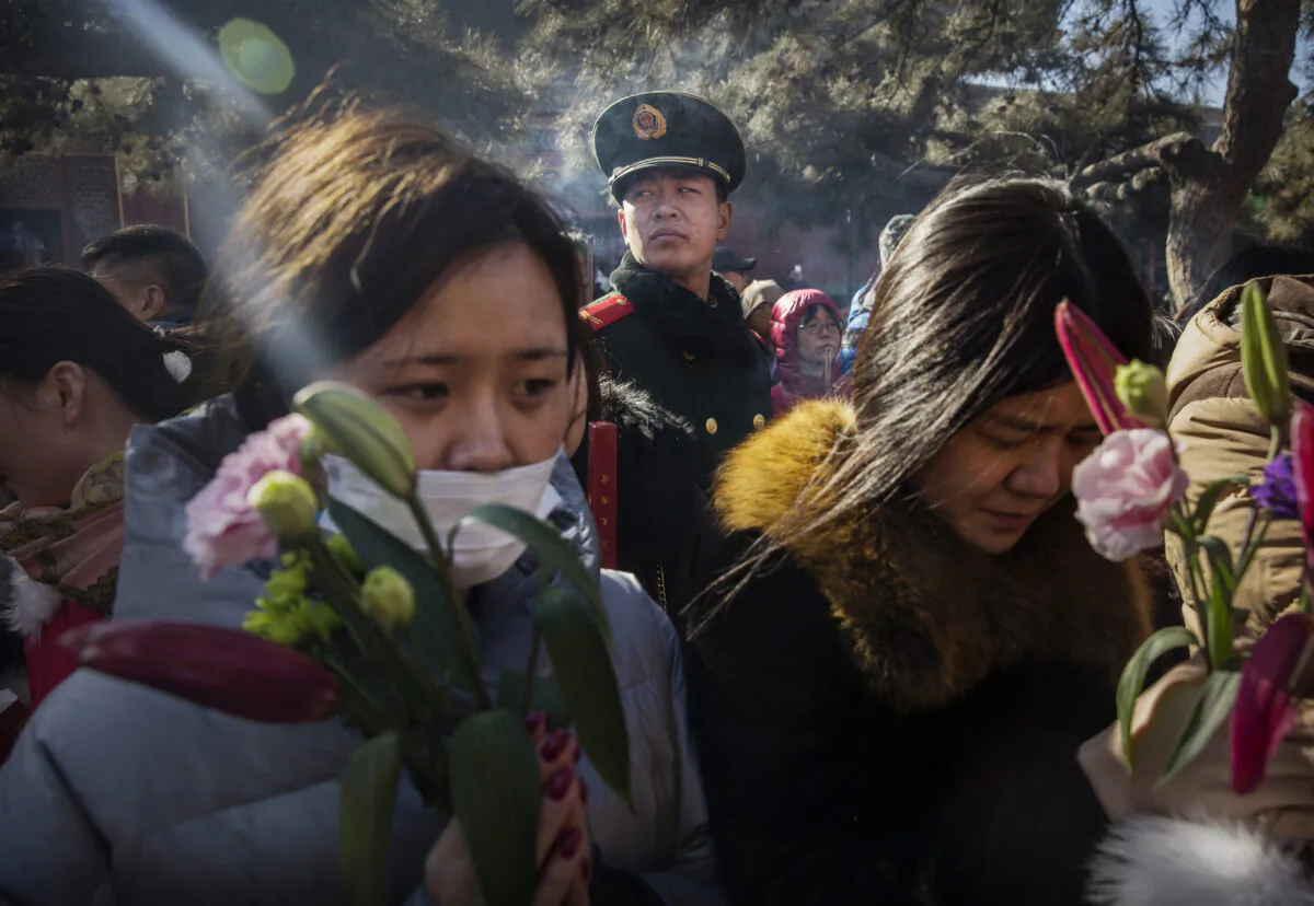 A Paramilitary police officer watches over  Chinese worshippers as they pray at the Yongchegong Lama Temple in Beijing, China, on Feb. 8, 2016. (Kevin Frayer/Getty Images)
