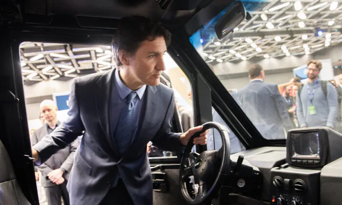 Prime Minister Justin Trudeau looks into the cabin of an electric utility truck during a visit to Impulsion, the International Summit on Electric and Smart Transportation, in Montreal on March 13, 2023. (The Canadian Press/Graham Hughes)