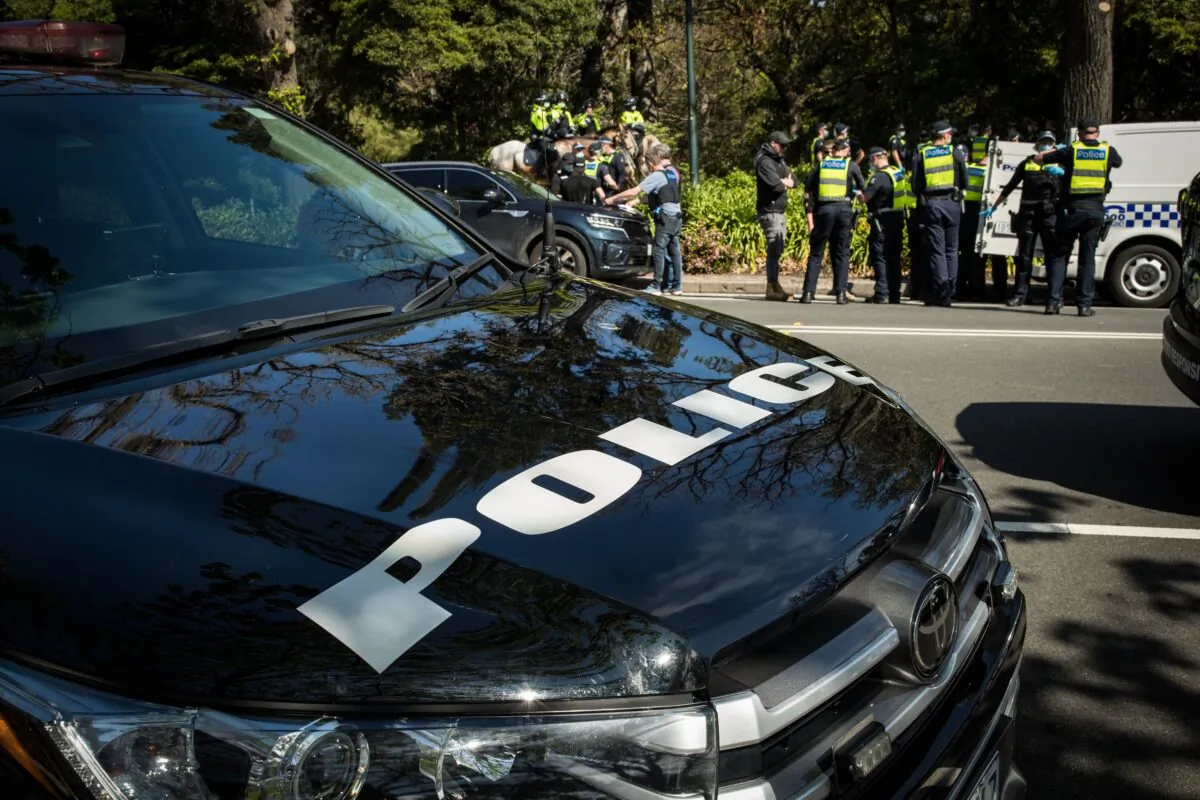 A protester is detained and questioned by members of Victoria Police on the 'Tan' running track in Melbourne, Australia, on Oct. 2, 2021. (Darrian Traynor/Getty Images)