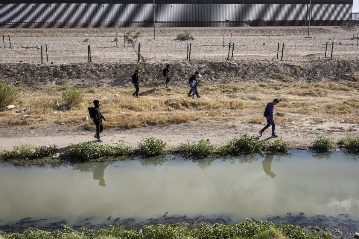 Honduran immigrants walk along the U.S. side of the Rio Grande and past an emptied-out migrant camp after crossing over from Mexico to El Paso, Texas, on May 13, 2023. (John Moore/Getty Images)