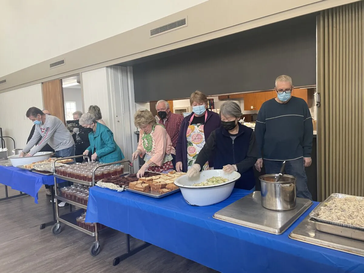 Volunteers line up at St. Luke's Episcopal Church to serve meals to those in need in Long Beach, Calif., on May 13, 2023. (Carol Cassis/The Epoch Times)