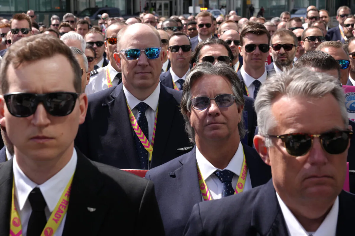 WestJet Airlines pilots assemble for a group photo after standing on a picket line at Toronto's Pearson Airport on May 8, 2023. The picket is one of three at Canada’s largest airports to show WestJet management they remain committed to negotiating a North American industry-standard contract. (Chris Young/The Canadian Press)
