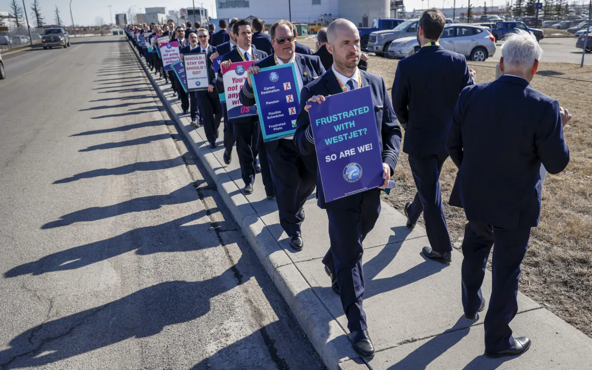 Members of the Air Line Pilots Association demonstrate amid contract negotiations outside the WestJet headquarters in Calgary, Alta., on March 31, 2023. (Jeff McIntosh/The Canadian Press)