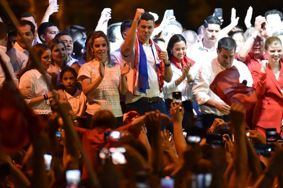 Paraguayan presidential candidate for the Colorado Party, Santiago Peña (C), celebrates next to with his wife, Leticia Ocampos de Pea (L), and Paraguayan former President Horacio Cartes, after winning the presidential election in Asuncion on April 30, 2023. - Paraguayans on Sunday elected a president from the rightwing Colorado Party, in power for nearly eight decades, rejecting a center-left challenger who had railed against institutional corruption. (Photo by NORBERTO DUARTE / AFP) (Photo by NORBERTO DUARTE/AFP via Getty Images)