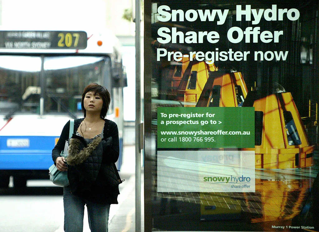 A woman passes by an advertisement of Snowy Hydro share initial public offering (IPO) in Sydney, 02 June 2006. (David Hancock/AFP via Getty Images)