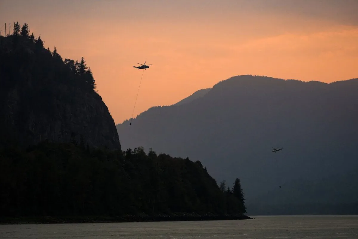 Helicopters with water buckets battling the Flood Falls Trail wildfire pick up water from the Fraser River, in Hope, B.C., Sept. 12, 2022. (The Canadian Press/Darryl Dyck)