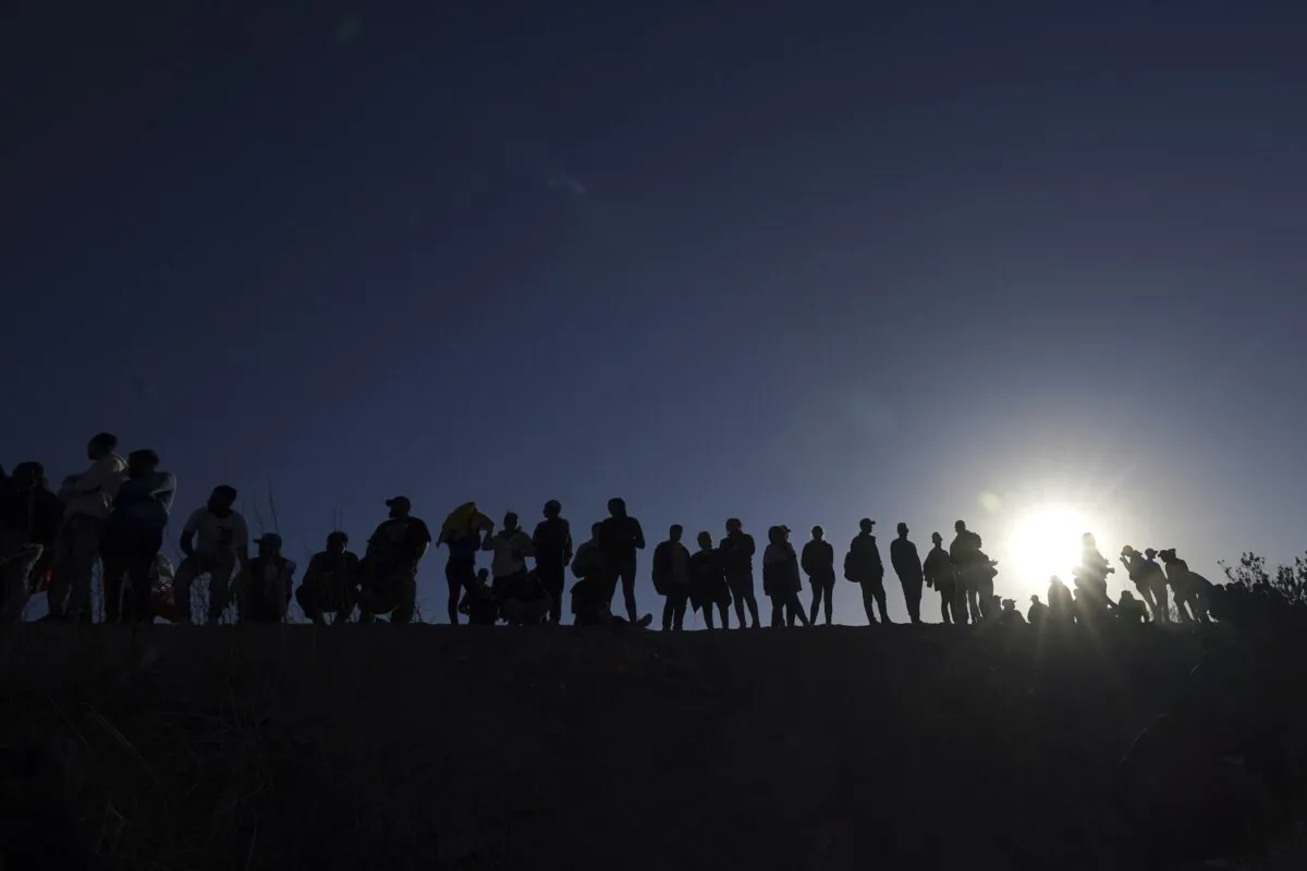Migrants stand on the Mexican side of the U.S.-Mexico border, on the banks of the Rio Grande, in Ciudad Juarez, Mexico, on March 29, 2023. (Fernando Llano/AP Photo)