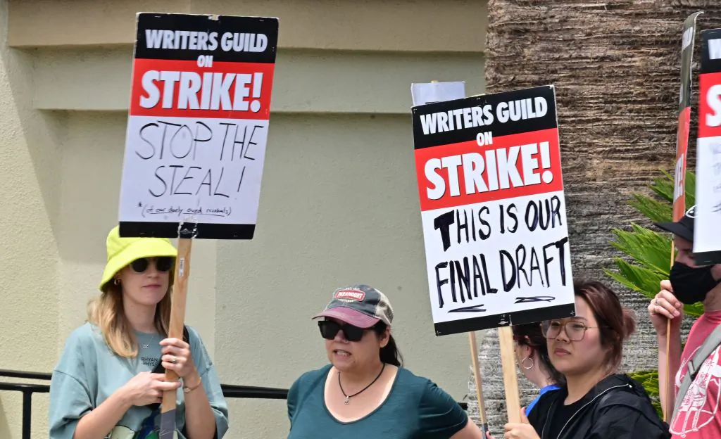 Writers hold signs while picketing in front of Paramount Studios in Los Angeles on May 15, 2023, as the strike by the Writers Guild of America enters its third week. The thousands of picketing writers say they are striking for better compensation in a field that has been disrupted by the streaming industry. Writers say they are looking for more stable working conditions and a better share of the profits generated by the rise of streaming. (Frederic J. Brown/AFP via Getty Images)