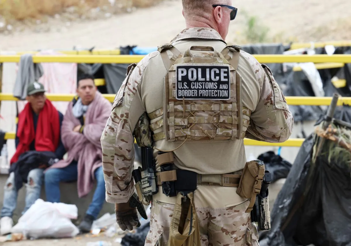 A Customs and Border Protection officer keeps watch as immigrants are transported from a makeshift camp between border walls between the U.S. and Mexico in San Diego on May 13, 2023. (Mario Tama/Getty Images)