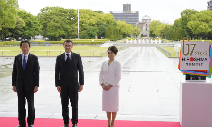French President Emmanuel Macron (C) is welcomed by Japanese Prime Minister Fumio Kishida and First Lady Yuko Kishida during a visit to the Peace Memorial Park on the sidelines of the G-7 summit in Hiroshima, Japan, on May 19, 2023. The G-7 summit will be held in Hiroshima from May 19–22. (Franck Robichon/Pool/Getty Images)