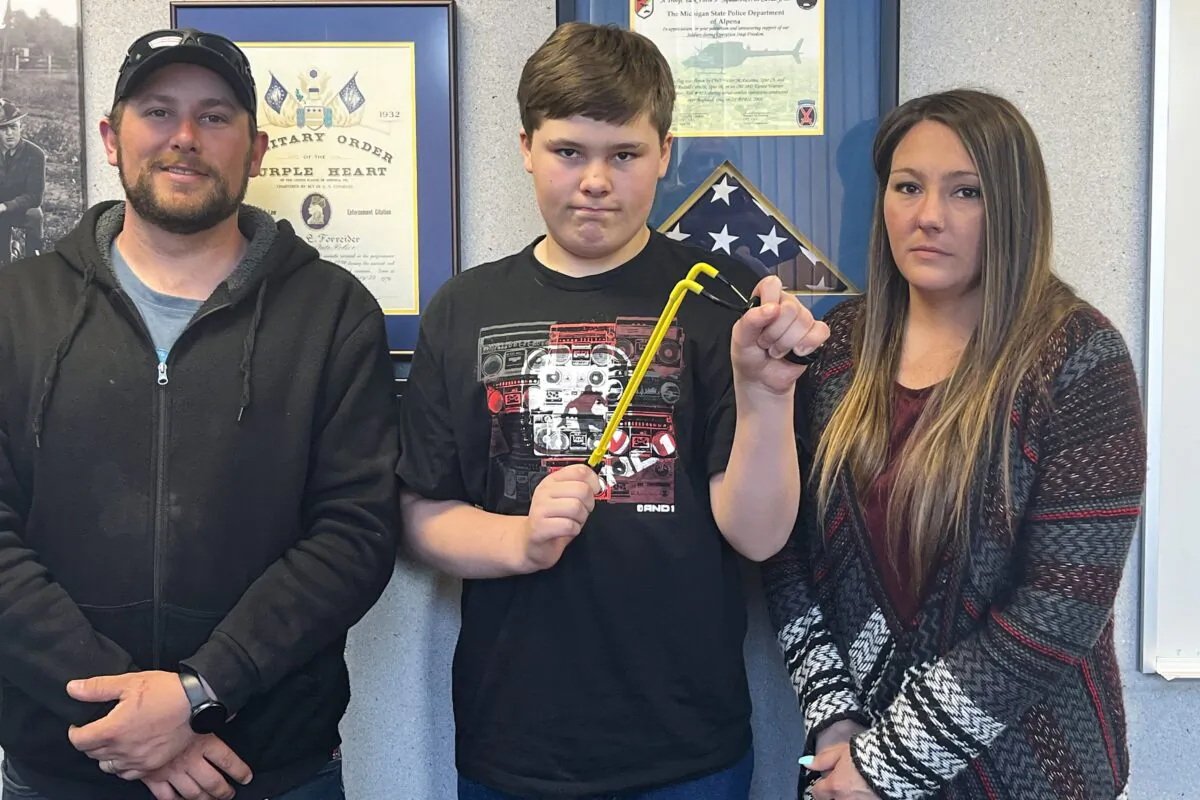 Andrew Burns (L), Owen Burns (C), and Margaret Burns pose with a slingshot Owen used to thwart an alleged May 10 kidnapping attempt of his sister in Alpena Township, Mich., on May 17, 2023. (Steve Schulwitz/The Alpena News via AP)