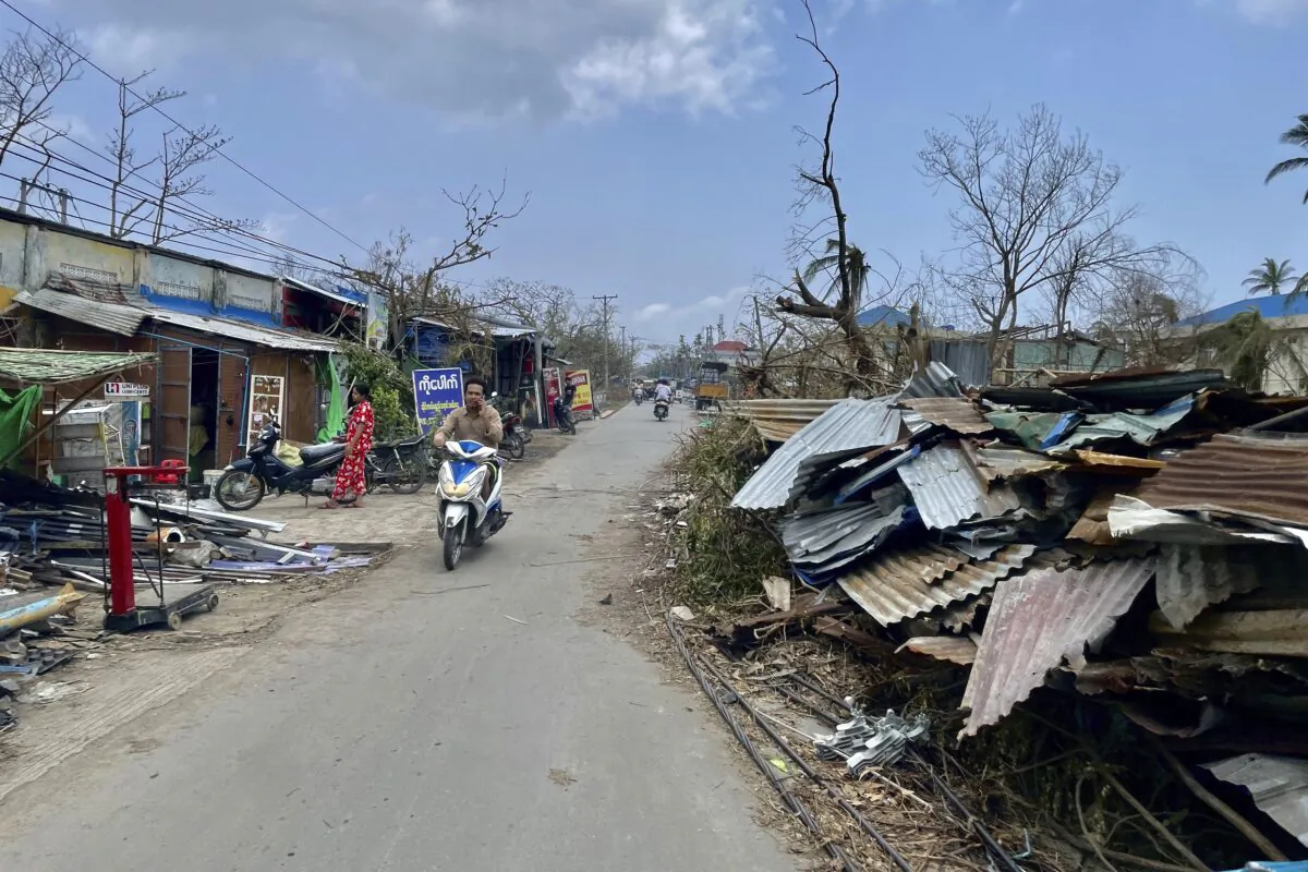 Local people ride motorbike along a roadside with damaged buildings after Cyclone Mocha in Sittwe township, Rakhine State, Burma, on May 19, 2023. (AP Photo)