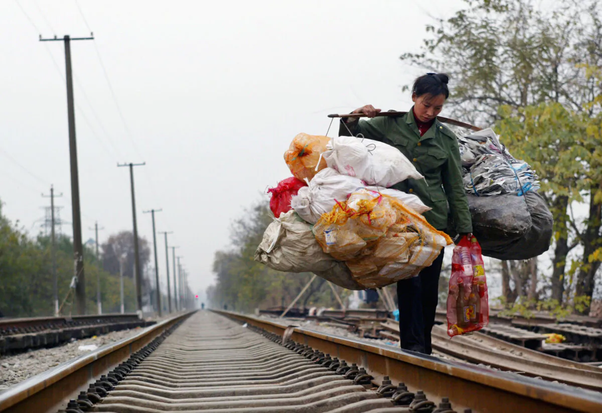 A Chinese migrant worker carrying rubbish walks on a railway in Wuhan, Hubei Province, China, on Dec. 6, 2004. (China Photos/GettyImages)