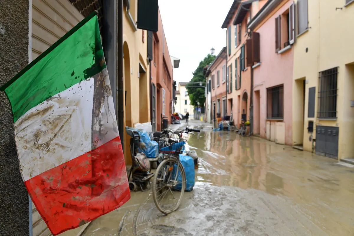 An Italian flag covered in mud flutters on a flooded street, after heavy rains hit Italy's Emilia Romagna region, in Castel Bolognese, Italy, on May 18, 2023. (Jennifer Lorenzini/Reuters)