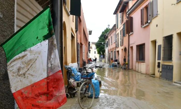 An Italian flag covered in mud flutters on a flooded street, after heavy rains hit Italy's Emilia Romagna region, in Castel Bolognese, Italy, on May 18, 2023. (Jennifer Lorenzini/Reuters)