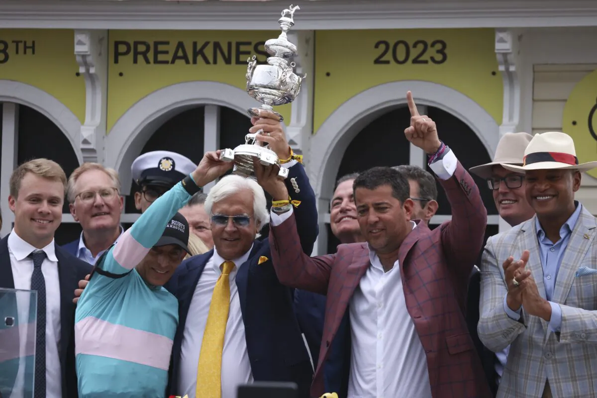 Bob Baffert (C), trainer of National Treasure, and jockey John Velazquez (L) help hoist the Woodland Vase after winning the148th running of the Preakness Stakes horse race at Pimlico Race Course in Baltimore on May 20, 2023. (Julia Nikhinson/AP Photo)