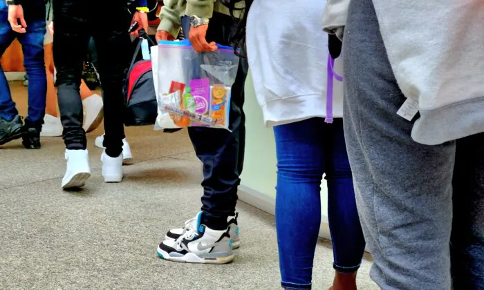 Illegal immigrants wait in line on May 17, 2023, as they prepare to board charter buses bound for other U.S. cities, paid for by the city of Denver, Colo. (Allan Stein/The Epoch Times)