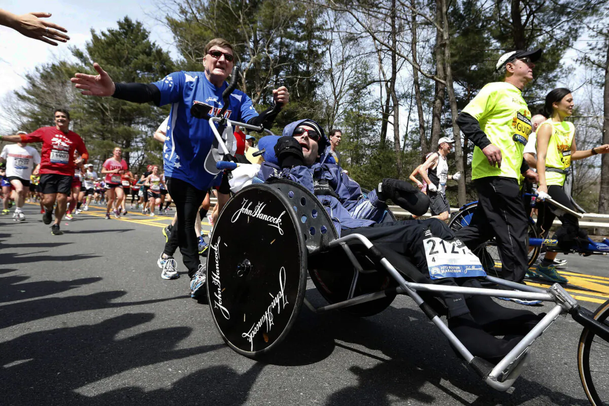 Rick Hoyt (C) is pushed by his father Dick (L) along the Boston Marathon course in Wellesley, Mass., on April 15, 2013. (Michael Dwyer/AP Photo)