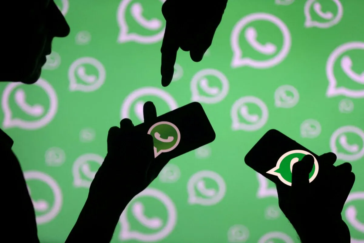 Men pose with smartphones in front of displayed Whatsapp logo on Sept. 14, 2017. (Dado Ruvic/Reuters)