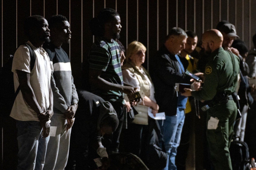 Illegal immigrants wait to be transported by bus to Border Patrol processing facilities in Yuma, Ariz., on May 18, 2023. (John Fredricks/The Epoch Times)