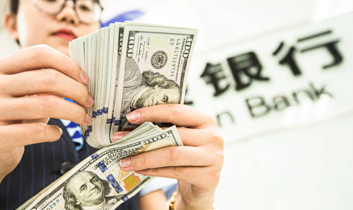 A Chinese bank employee counts U.S. dollar bills at a bank counter in Nantong in China's eastern Jiangsu Province on Aug. 6, 2019. (STR/AFP via Getty Images)