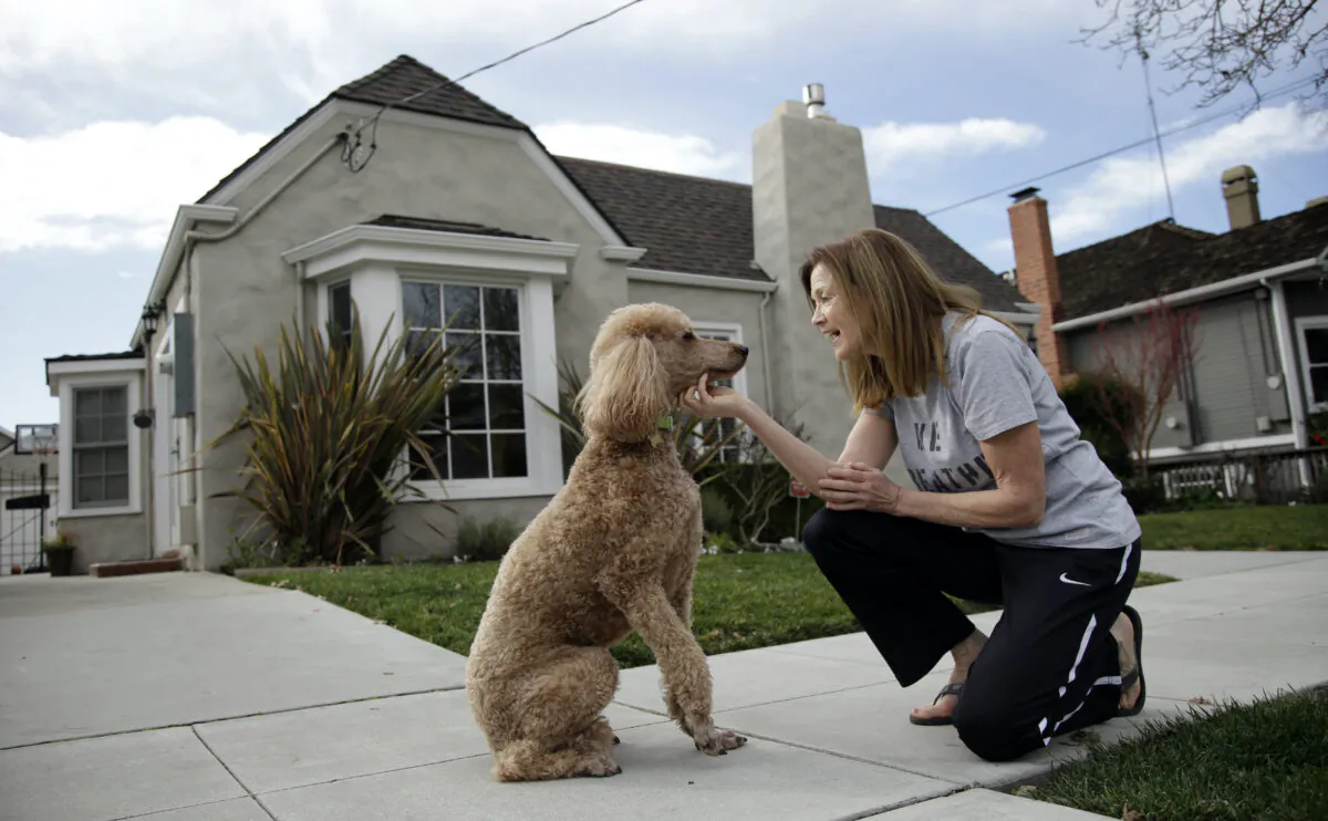 A woman poses with her dog outside her house in San Jose, Calif., on Jan. 15, 2016. (Marcio Jose Sanchez/AP Photo)