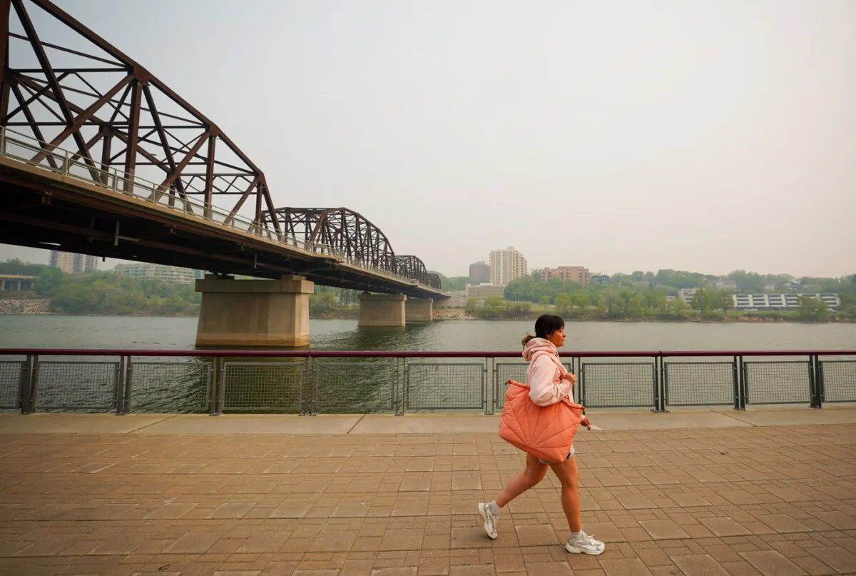 A person walks by the South Saskatchewan River in Saskatoon as smoke from wildfires burning across the Prairies blankets the city on May 20, 2023. (Heywood Yu/The Canadian Press)