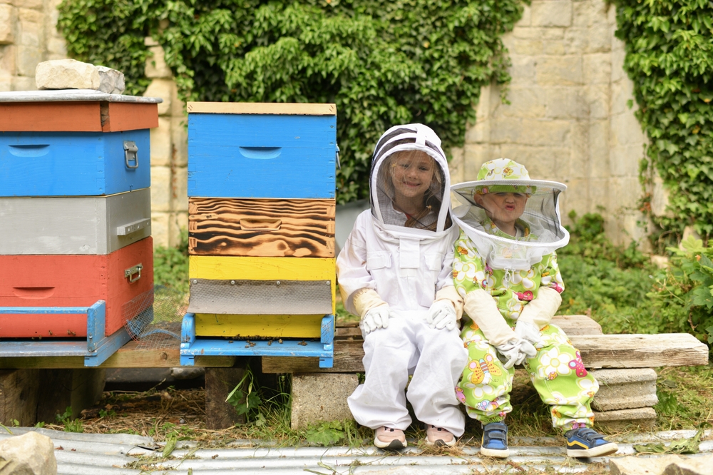 Children In Protective Suits Near The Beehive