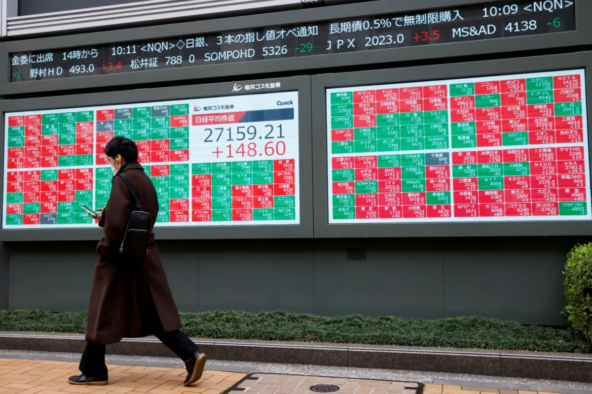 A man walks past an electronic board showing Japan's Nikkei average and stock prices outside a brokerage, in Tokyo, Japan, on March 17, 2023. (Androniki Christodoulou/Reuters)
