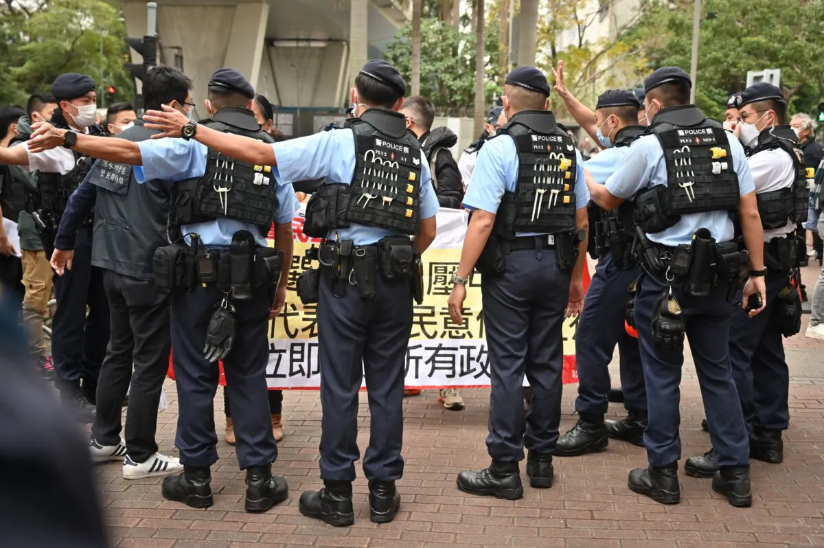 Members of the League of Social Democrats are surrounded by police as they carry a banner outside a court in Hong Kong on Feb. 6, 2023. (Peter Parks/AFP via Getty Images)
