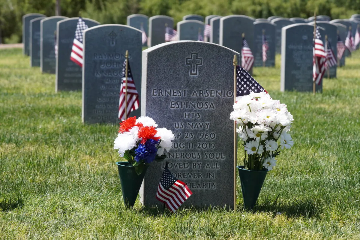 Carnations and daisies flank the gravestone of Ernest Arsenio Espinosa at the Arizona Veterans Memorial Cemetery in Marana, Ariz., on Memorial Day, May 27, 2023. (Allan Stein/The Epoch Times)