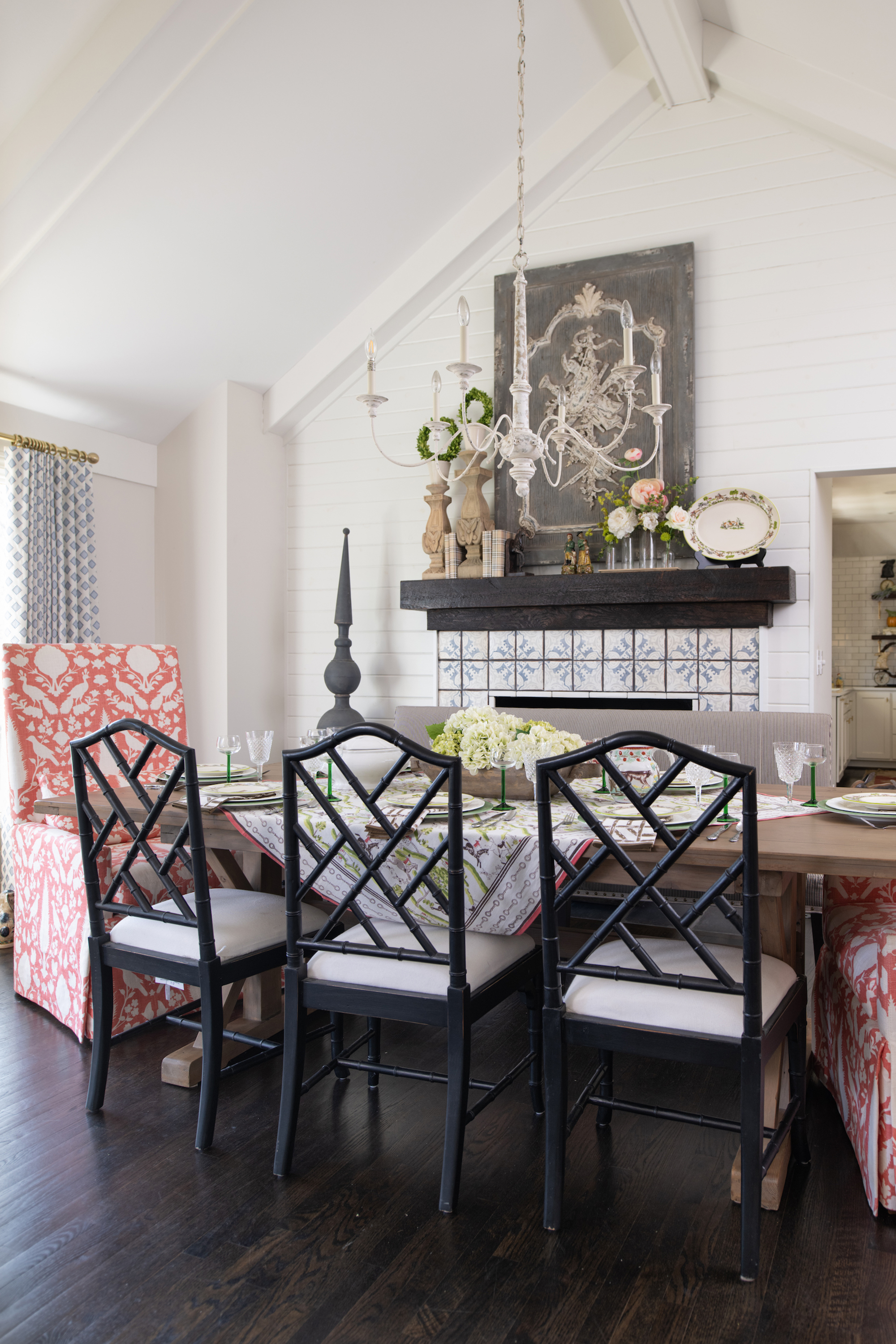 In the dining room, bamboo Chippendale chairs are pulled up to an expansive table, twin upholstered chairs in a coral colorway flank either side in a popular otomi pattern.