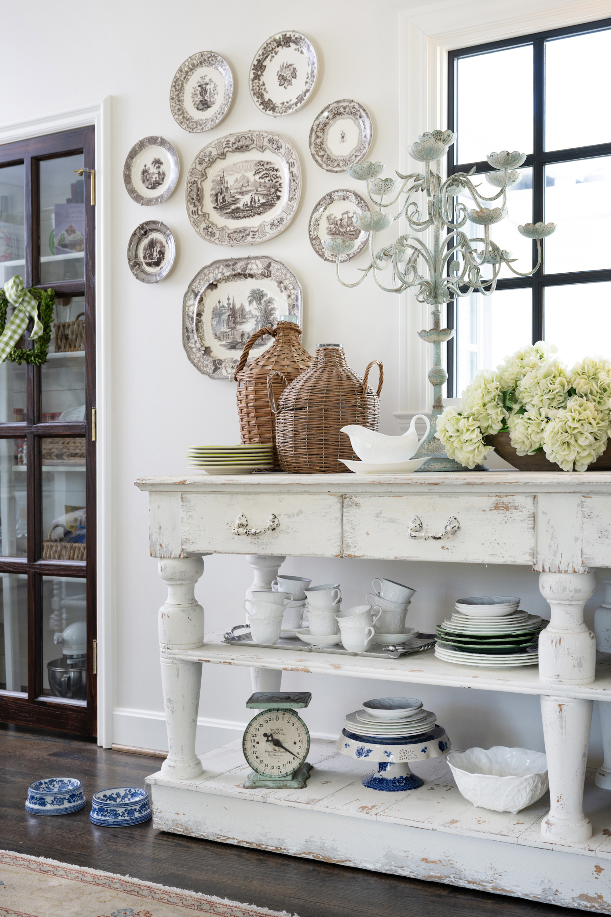 To the right of the pantry is a rustic vintage-inspired buffet layered with everyday pieces and stacks of dainty dishes. 