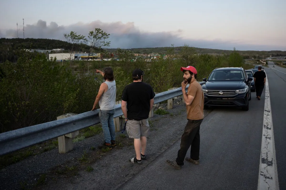 People stop on the side of the road where police set up a roadblock as heavy smoke fills the sky in a suburban community outside of Halifax on May 28, 2023. (The Canadian Press/Darren Calabrese)