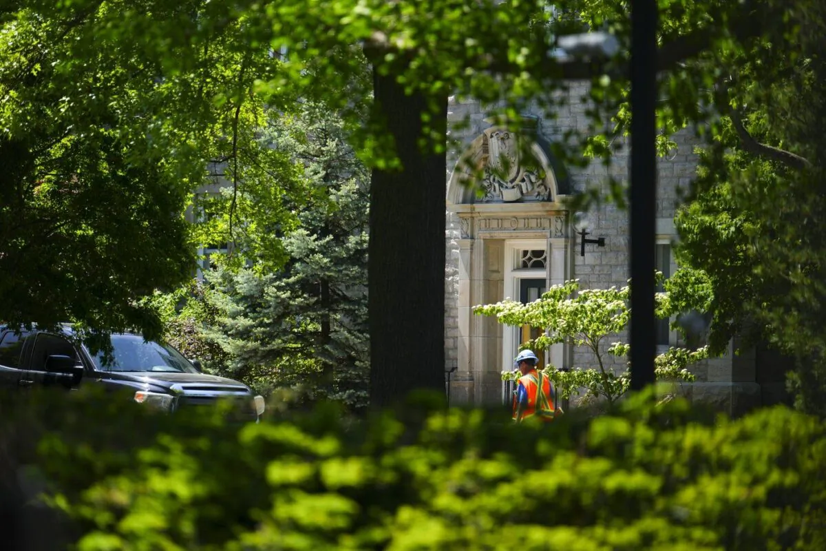 A construction worker walks past the front entrance to 24 Sussex Drive in Ottawa on May 29, 2023. (The Canadian Press/Sean Kilpatrick)