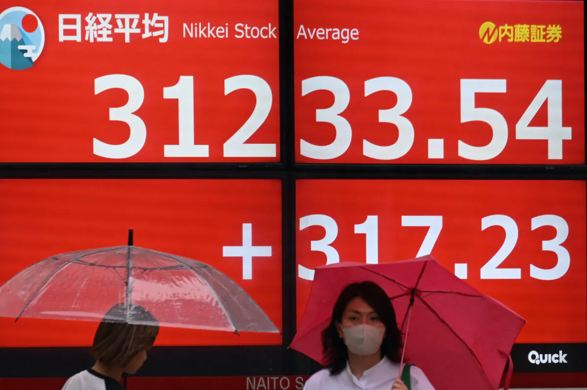 Pedestrians walk past an electronic display board showing the closing share price on the Tokyo Stock Exchange in Tokyo on May 29, 2023. (Kazuhiro Nogi/AFP via Getty Images)