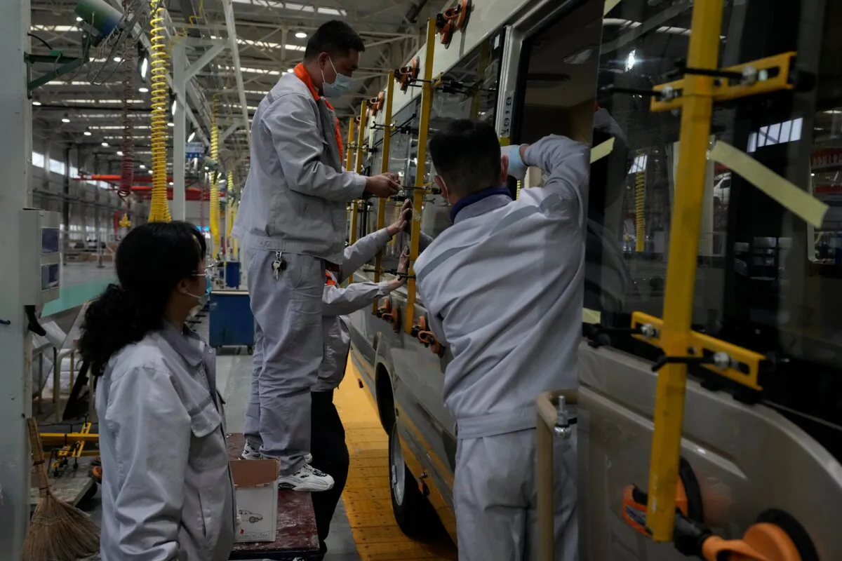 Workers install window panels on a minibus at a factory during a media organized tour in Shiyan city in central China's Hubei Province on May 10, 2023. (Andy Wong/AP Photo)