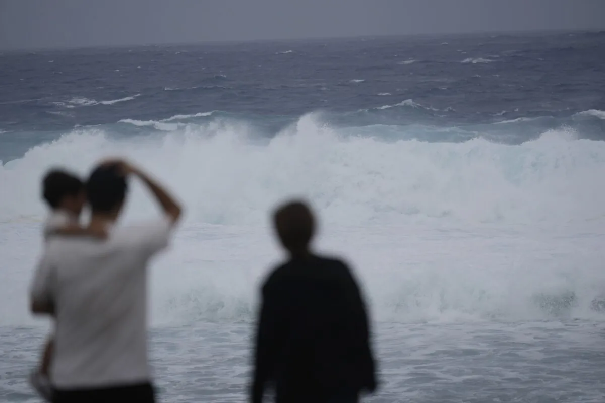 Family members watch waves affected by a severe weather system in Itoman, southern Japan, on May 31, 2023, as Typhoon Mawar moves towards the Okinawa islands. (Hiro Komae/AP Photo)