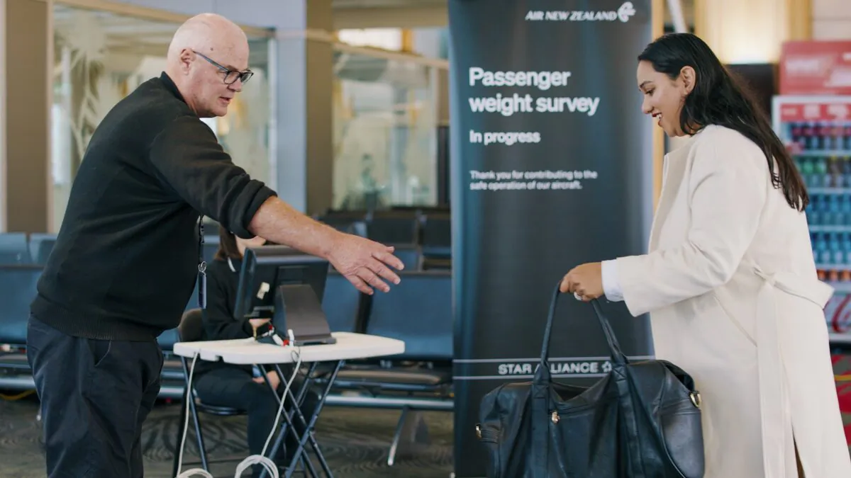 A woman hands her bag to a staff member to be weighed ahead of a flight in Auckland, New Zealand, on May 29, 2023. (Air New Zealand via AP)