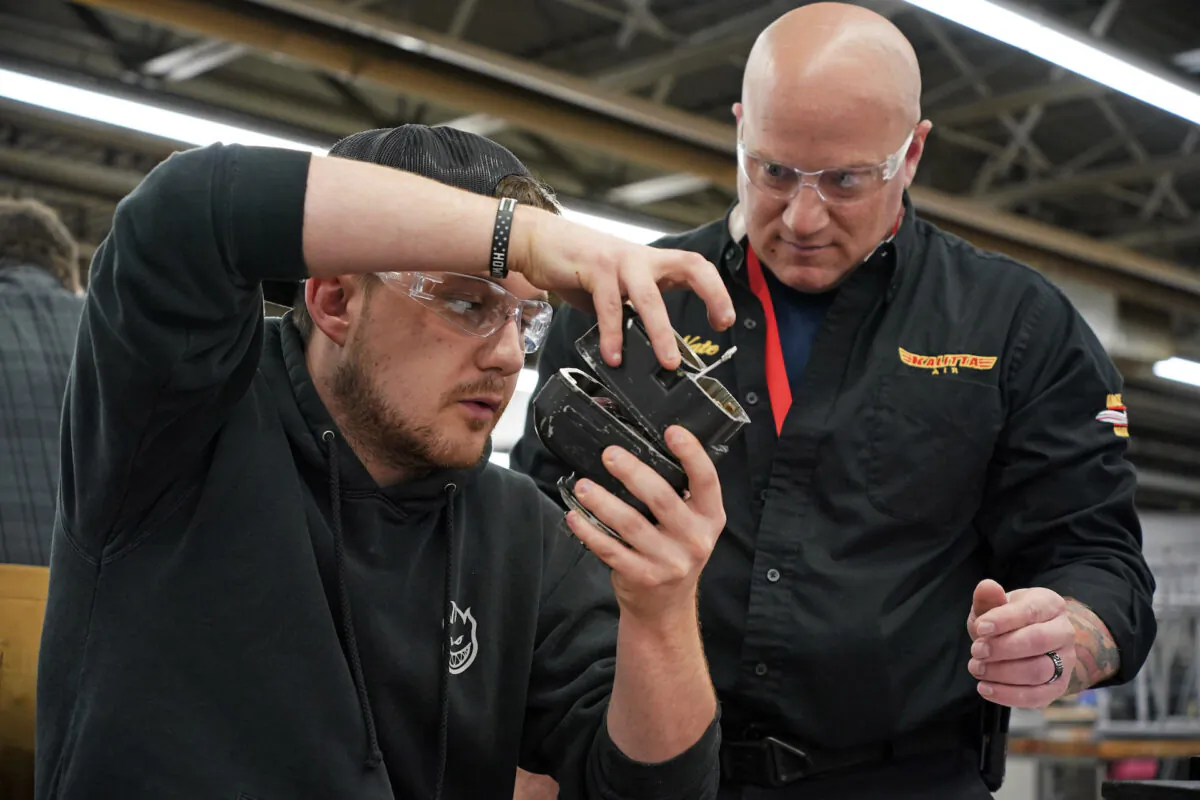 Steven Krasneski (L), a student at the Pittsburgh Institute of Aeronautics, studies a portion of an aircraft engine with help from Kalitta Air's Nate Vincenty-Cole in West Mifflin, Pa., on May 2, 2023. (Gene J. Puskar/AP Photo)