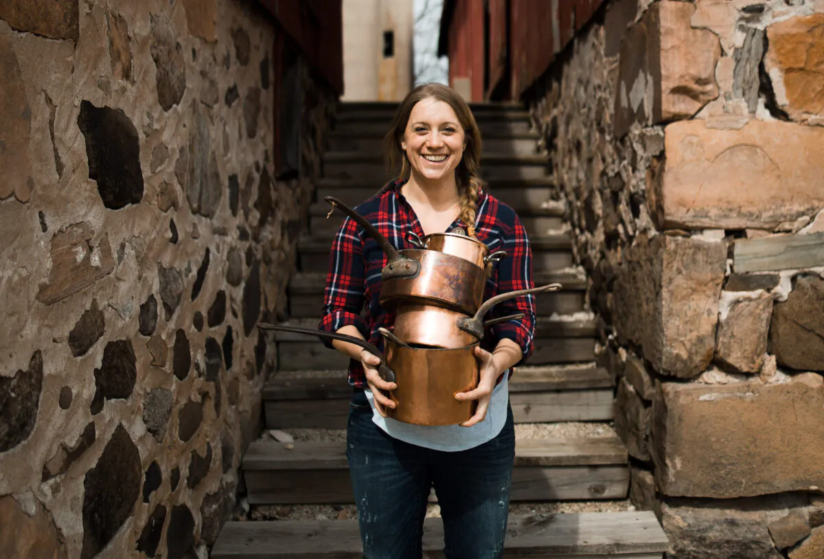 Sara Dahmen holds
a stack of restored
vintage copper
cookware and new
pieces built for her
own Americanmade
line. (Christian Watson)