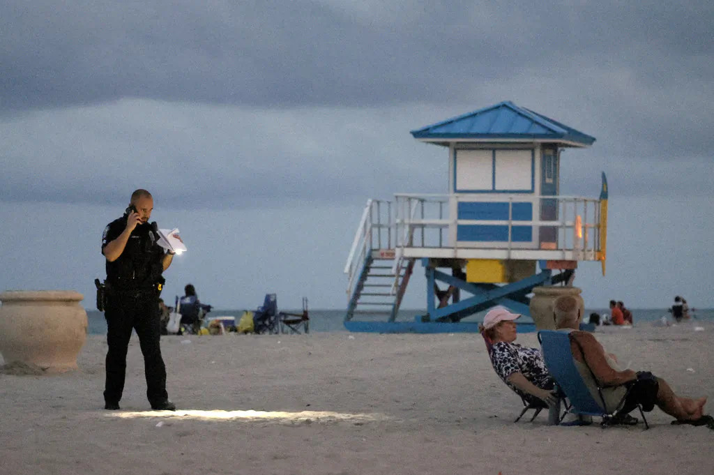 A police officer shines his flashlight downward while investigating a shooting in Hollywood, Fla., on May 29, 2023. (Mike Stocker/South Florida Sun-Sentinel via AP)
