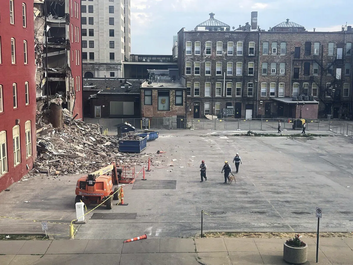 Three search and rescue workers and a dog approach the site of a building collapse during a search in Davenport, Iowa, on June 1, 2023. (Grace Kinnicutt/Quad City Times via AP)