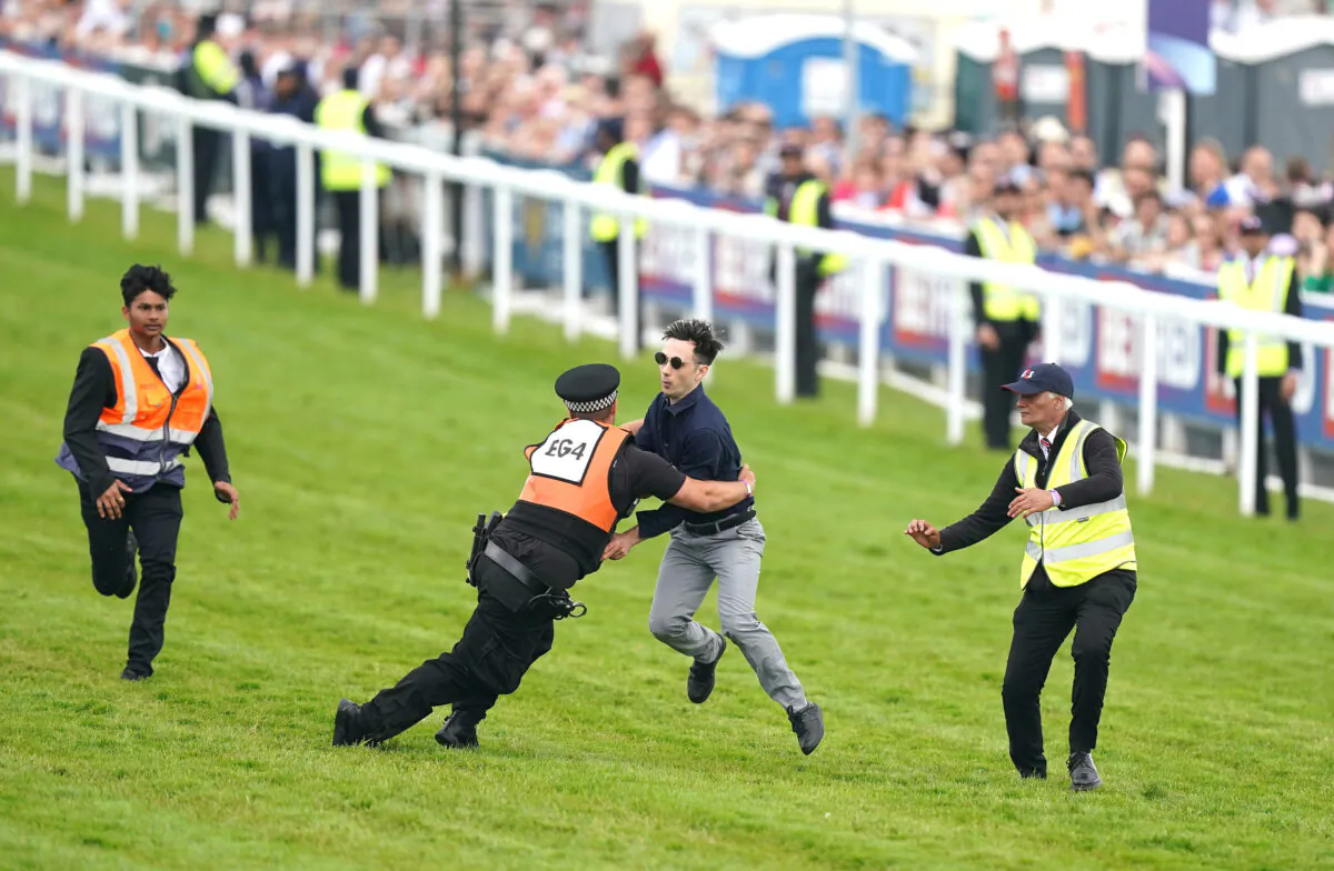 A protester is tackled by police and stewards shortly before the Derby at Epsom Downs racecourse in Surrey, England, on June 3, 2023. (PA)
