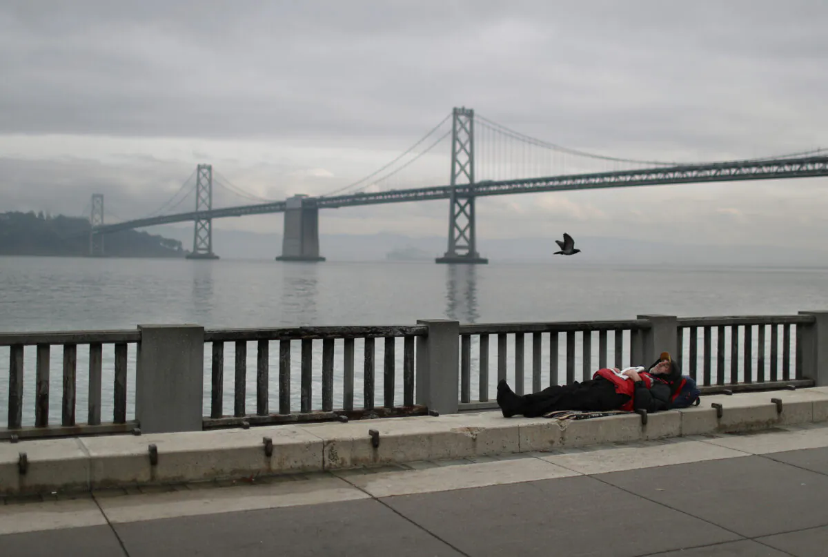A homeless man sleeps on the sidewalk near the San Francisco–Oakland Bay Bridge on Dec. 5, 2019 in San Francisco, Calif. (Justin Sullivan/Getty Images)